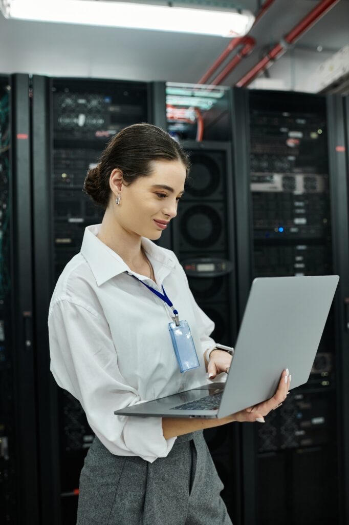 IT specialist in a white shirt engages with a laptop among server hardware in a data center.