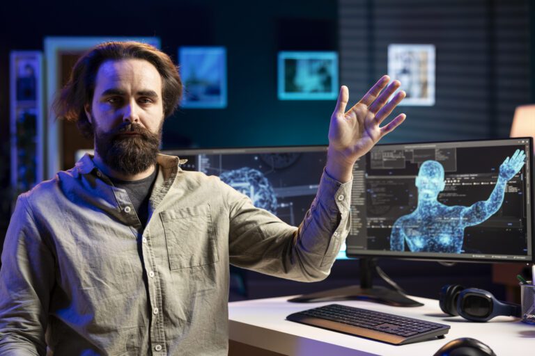 A man raises his hand in front of two computer monitors displaying digital human figures, seamlessly interacting with generative AI.