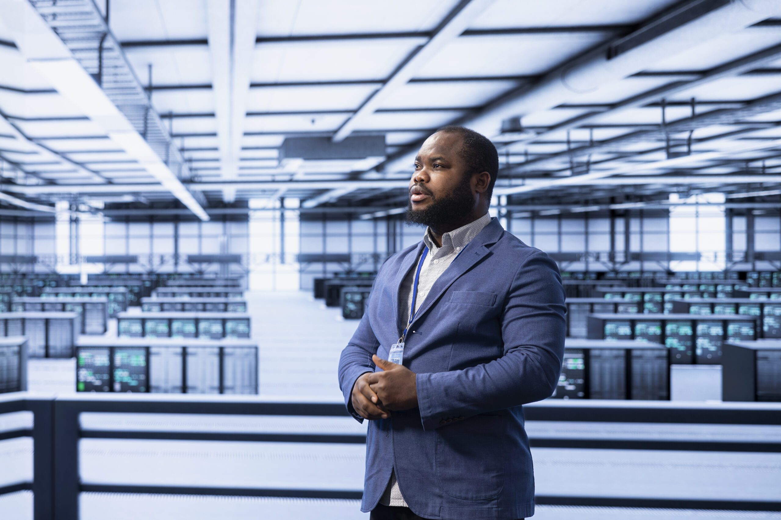 A person in a blue suit stands in a large data center, where rows of servers highlight the push to modernize infrastructure.