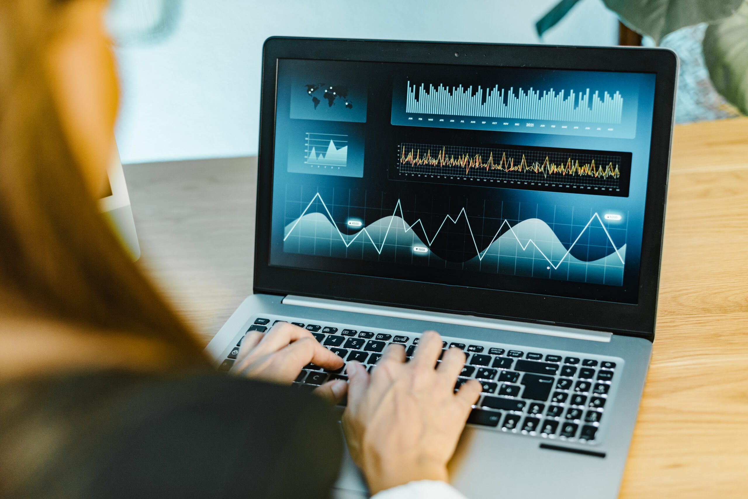 A person is intelligently analyzing data on a laptop, with various graphs and charts displayed on the screen.