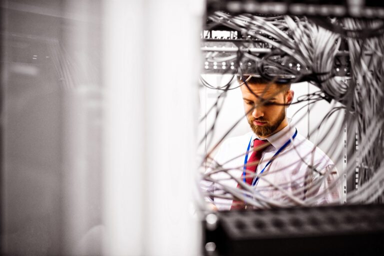 Technician checking cables in a rack mounted server in server room