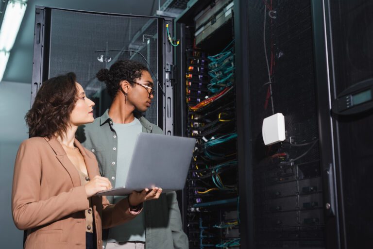 young interracial engineers with laptop making diagnostics of server in data center