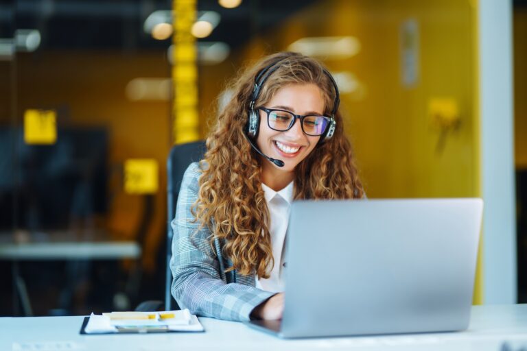 Call center agent with headset working on support hotline in modern office. Video conference.