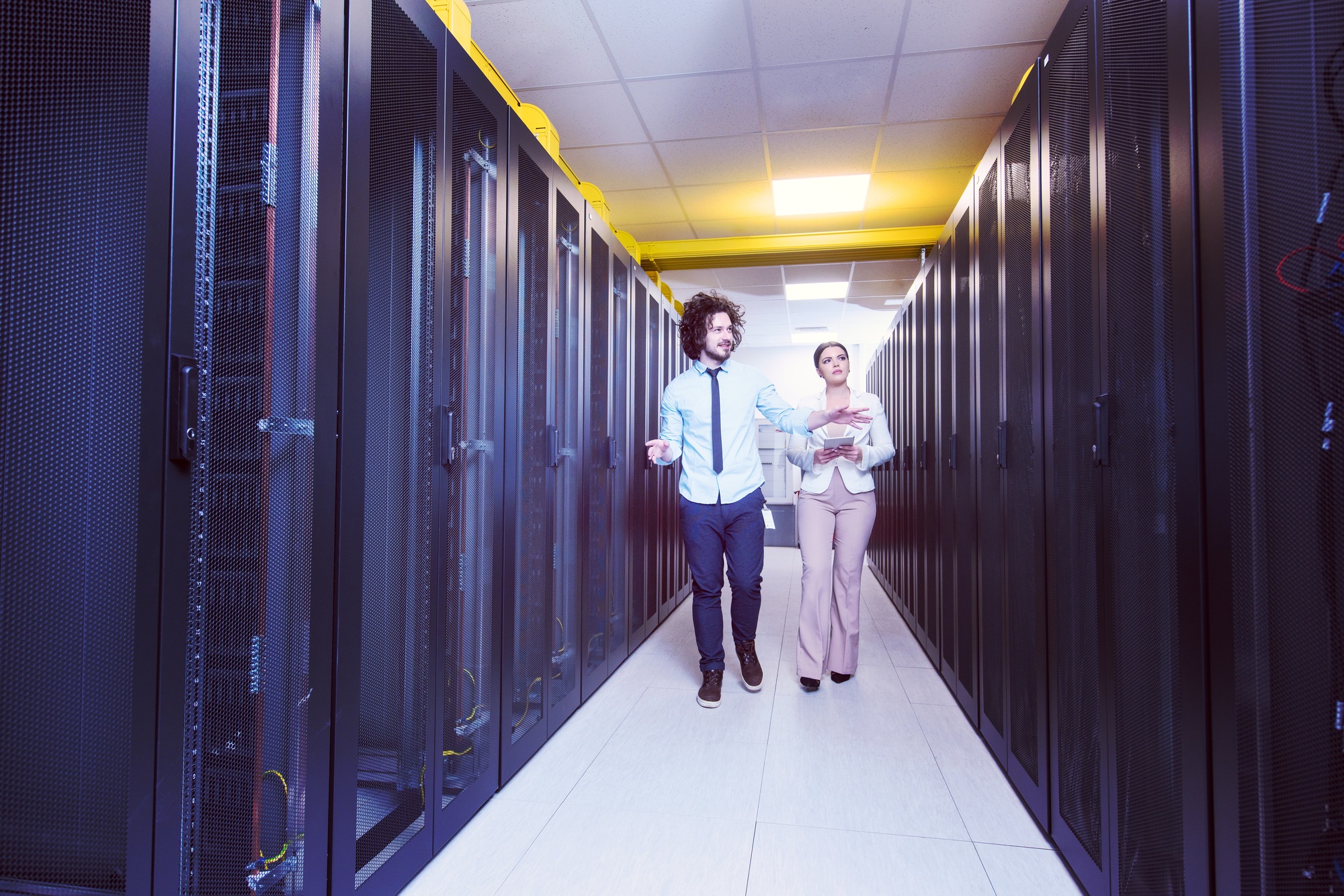 engineer showing working data center server room to female chief