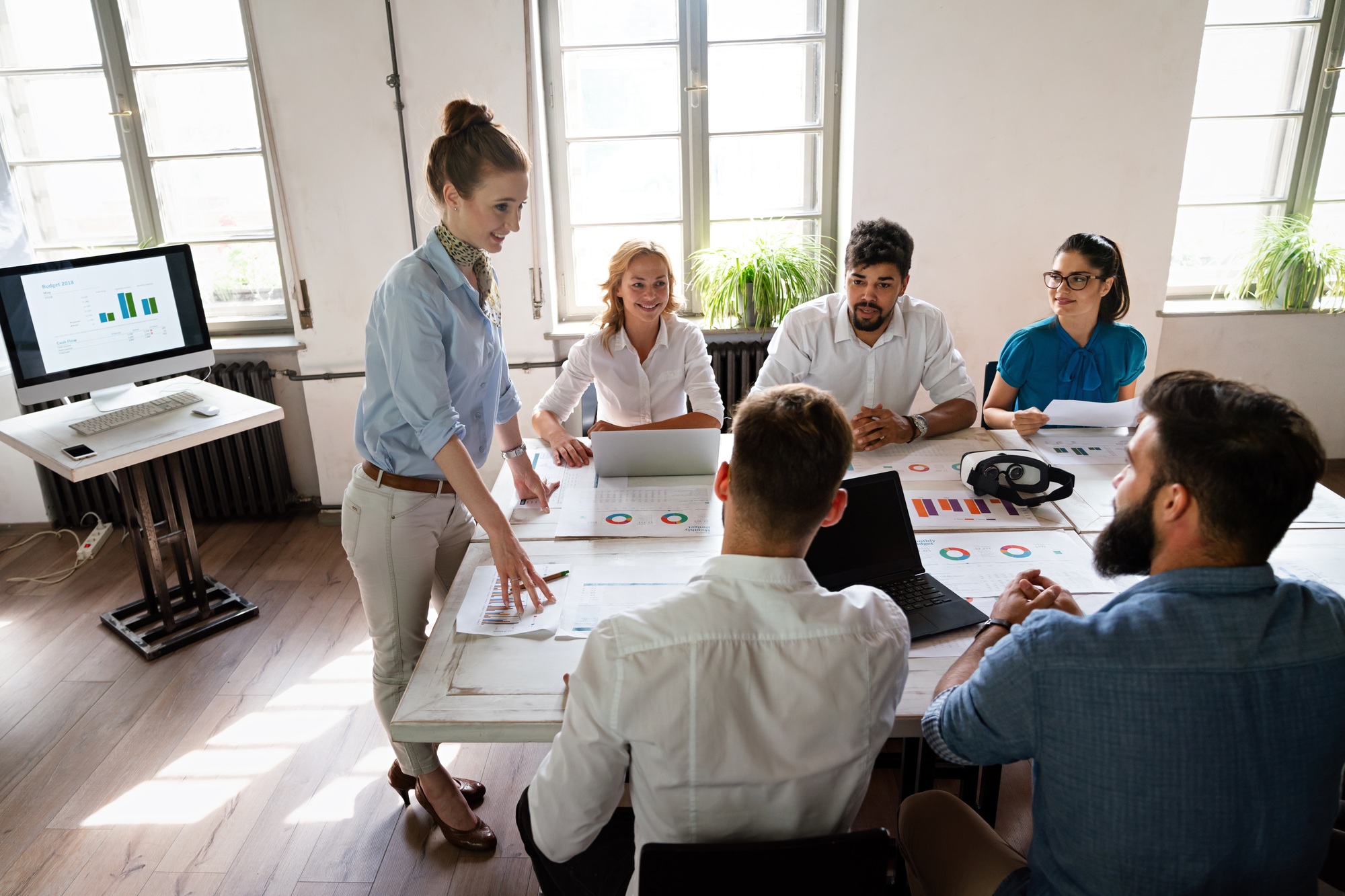 Group of young confident happy business people analyzing data during meeting in the office