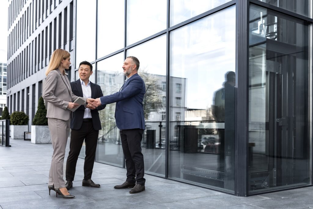 Meeting of three colleagues from outside the office building, experienced and mature IT specialists