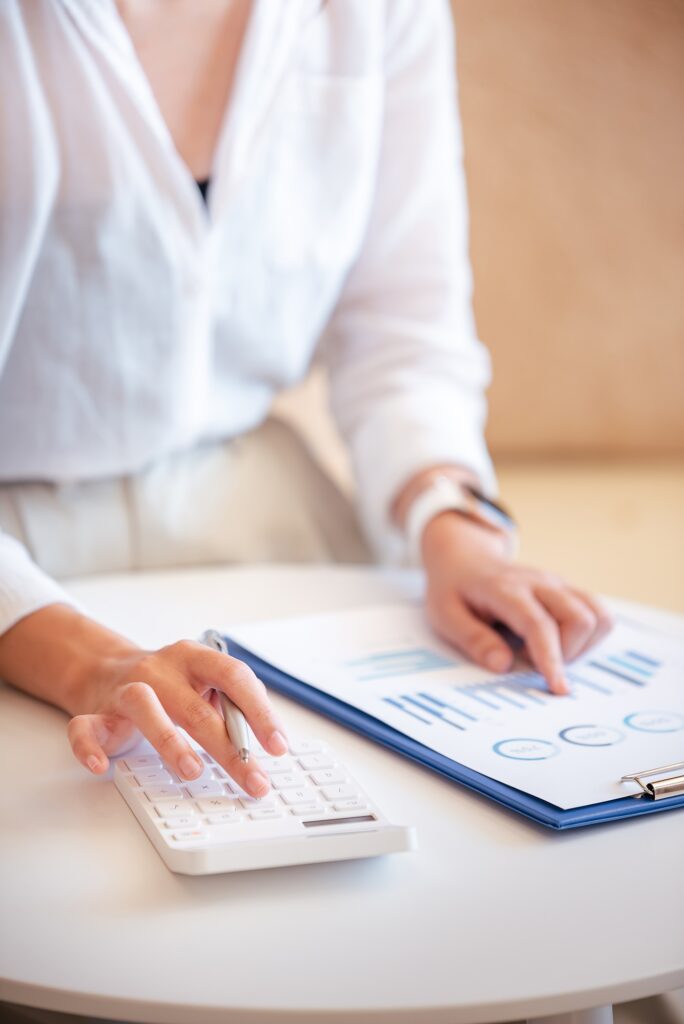 A young woman's hand presses a calculator to determine and summarize the cost of mortgage home loans