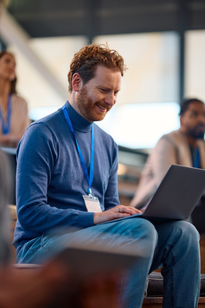 Happy businessman using laptop during a seminar in convention center.
