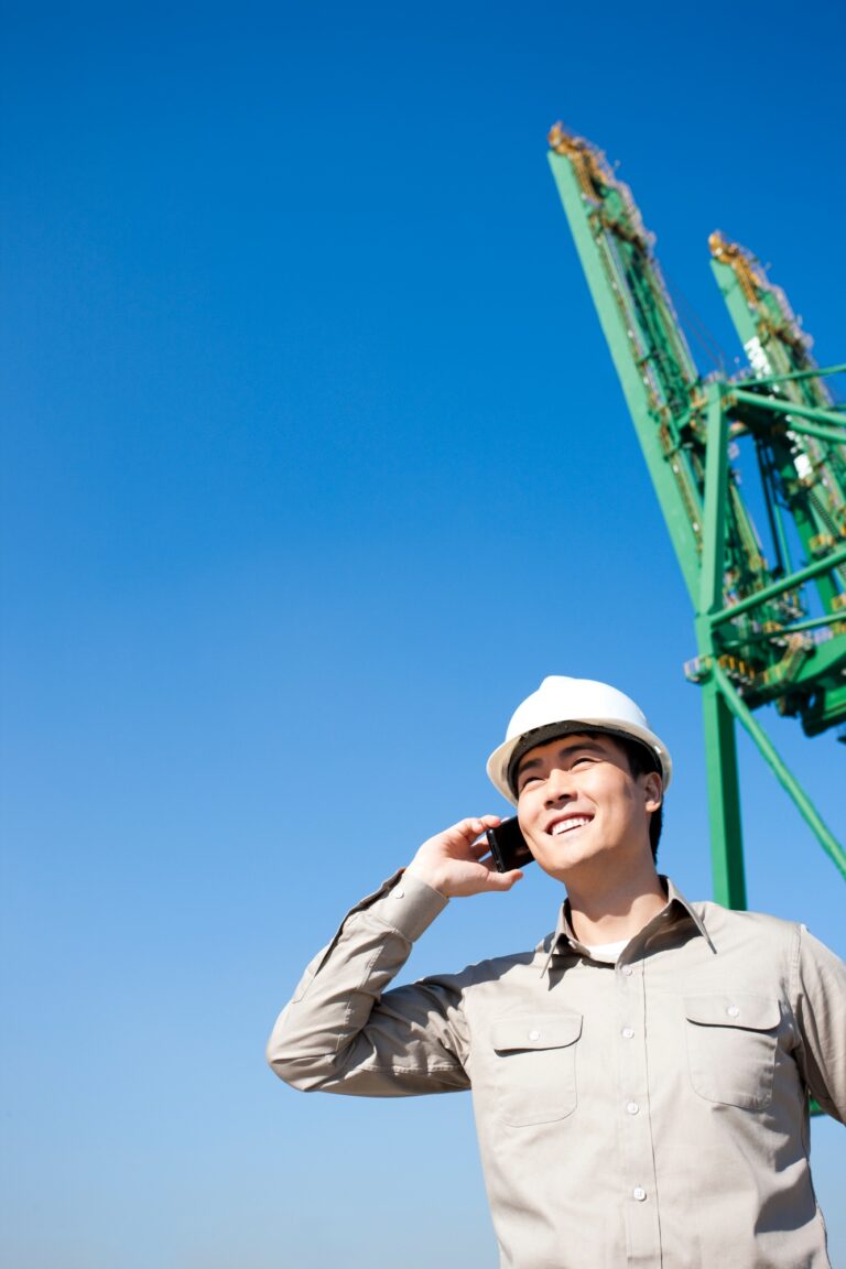 Male shipping industry worker on the phone with shipping dock background