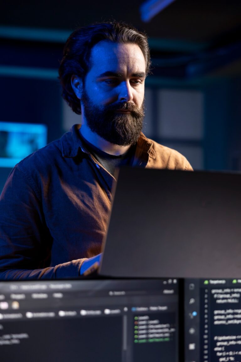 Teleworking IT admin working from RGB lit home using laptop