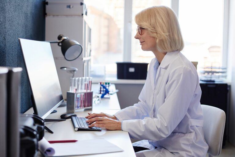 Female Lab Chemist Using Computer while Studying Chemicals in Pharmaceutical Laboratory