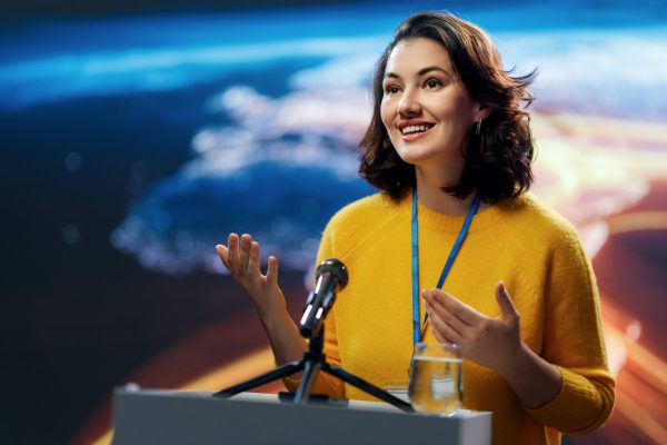 A young woman is giving a presentation at a conference.